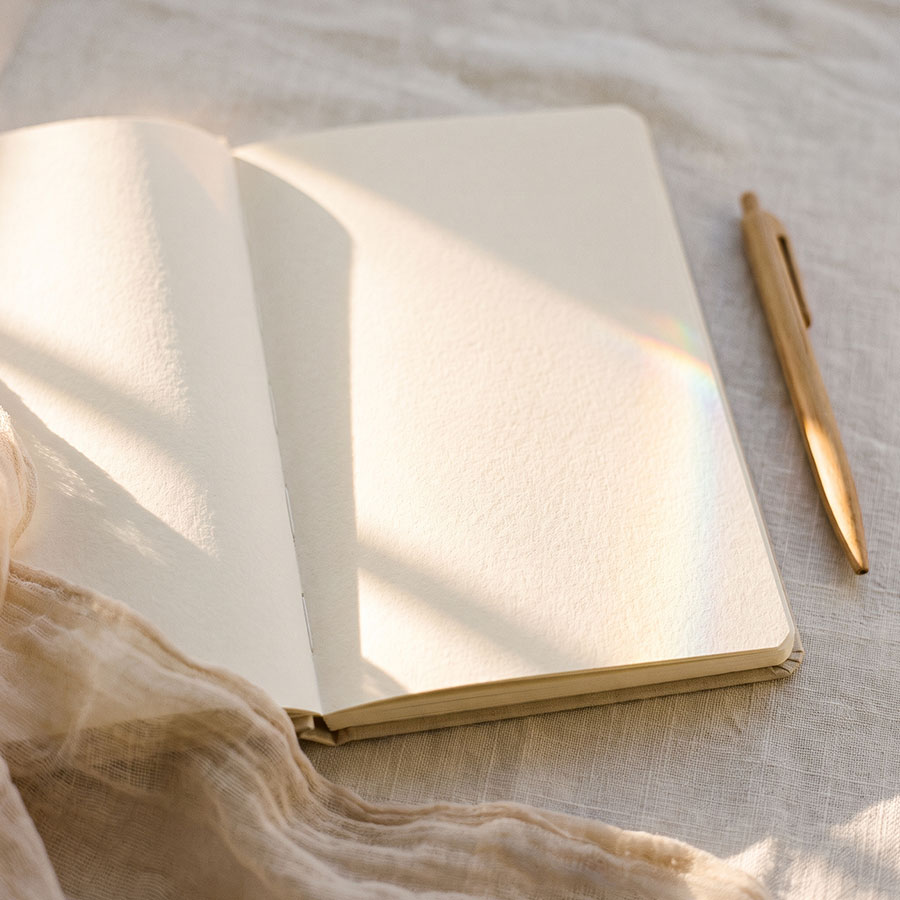 Aufgeschlagenes Notizbuch mit Stift im Morgenlicht